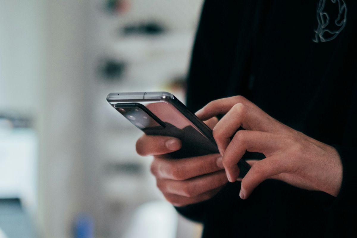 Egy modern nappaliban szemkímélés miatt egy férfi beállítja a telefonját